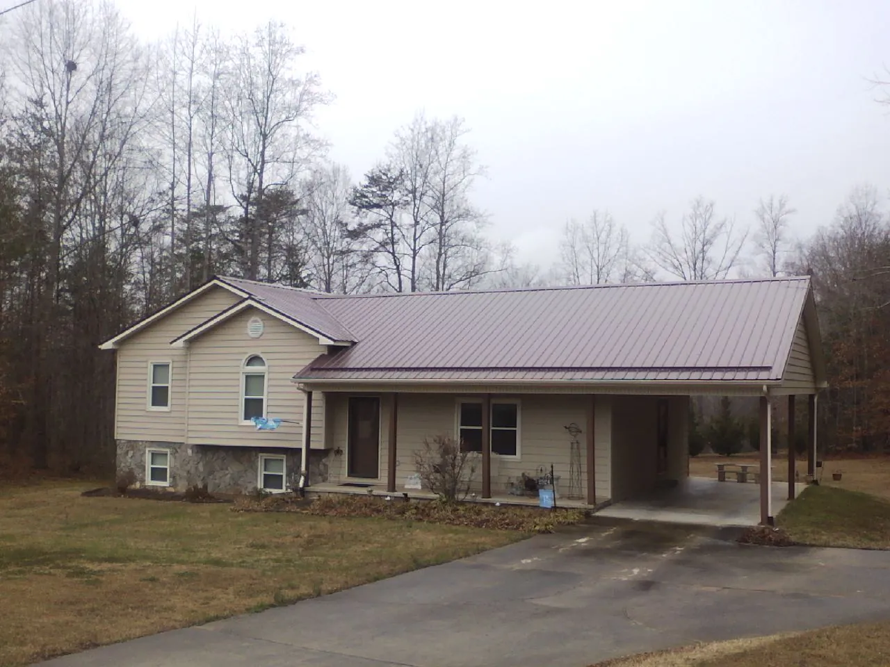 Burgundy metal roof on a tan split level home with an attached carport in Deer Lodge
