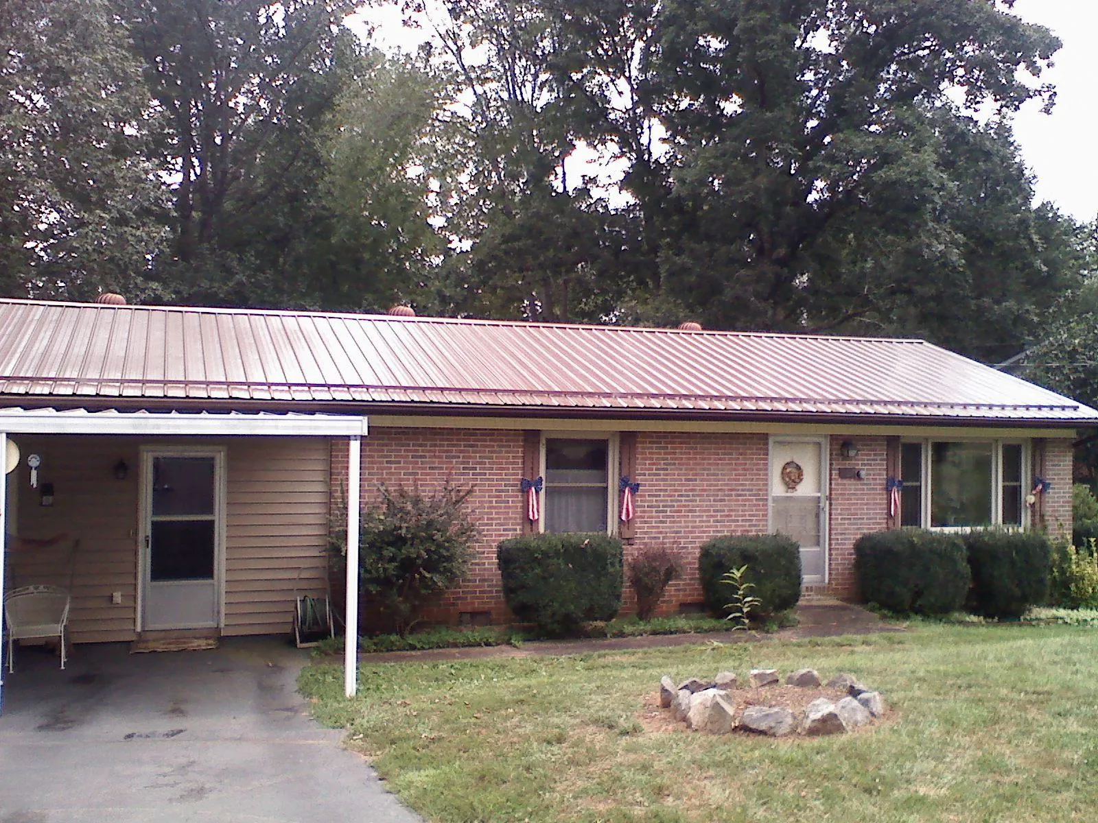 Bronze metal roof and carport on a brick ranch home — Roof Repair work by our crew in Deer Lodge